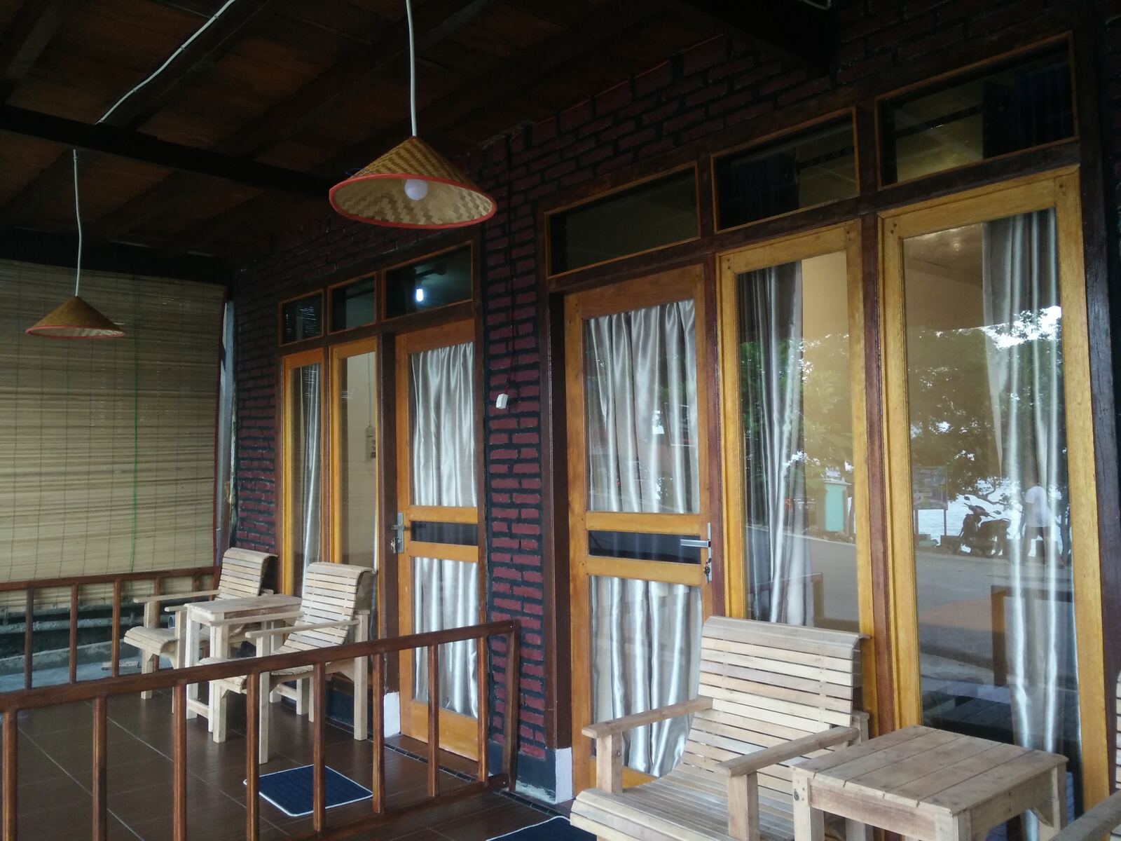 Beranda kamar Family dengan pemandangan pantai lewat jendela kayu